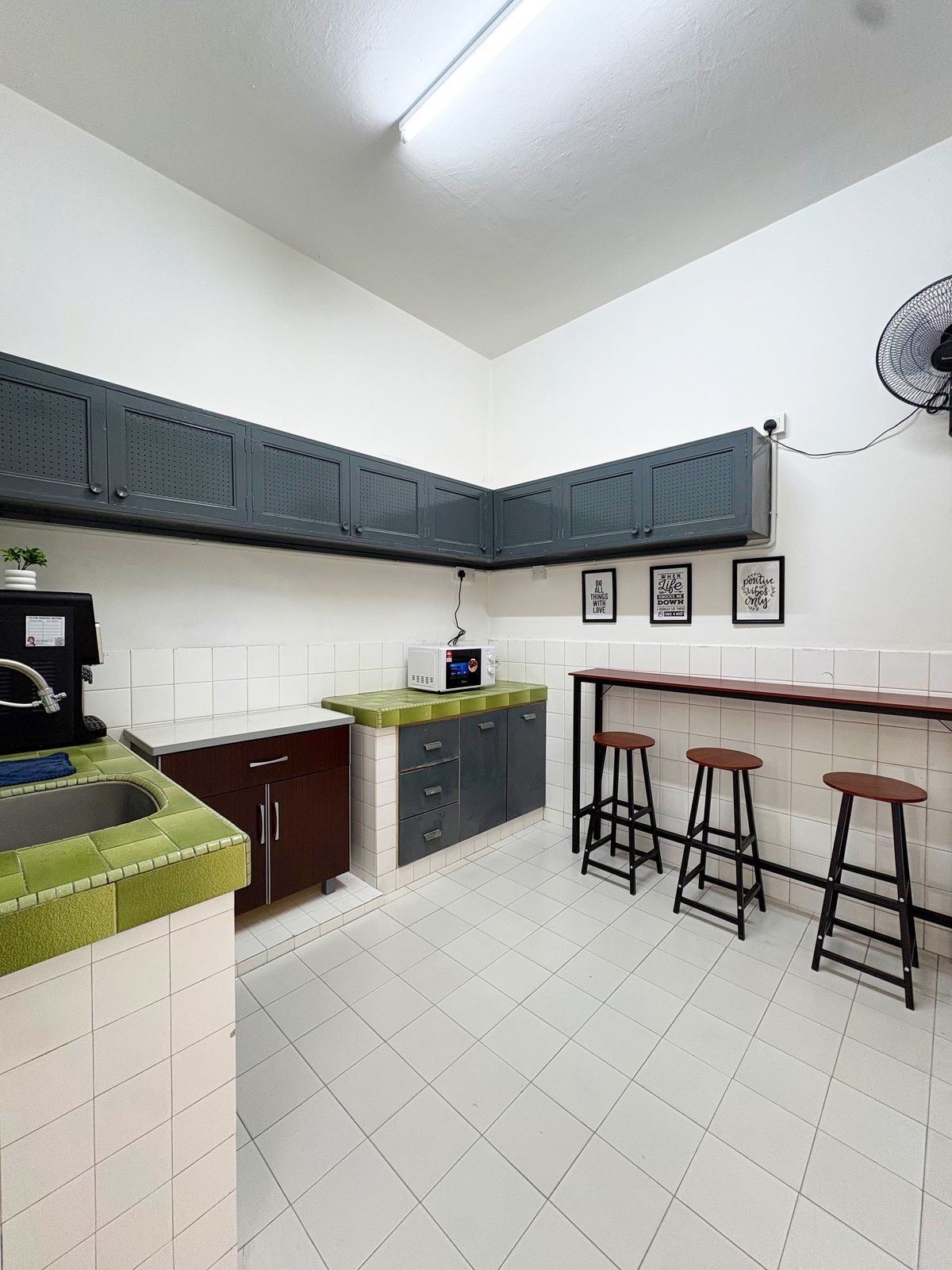 Shared kitchen with green tiled counters, microwave, and a breakfast bar with stools