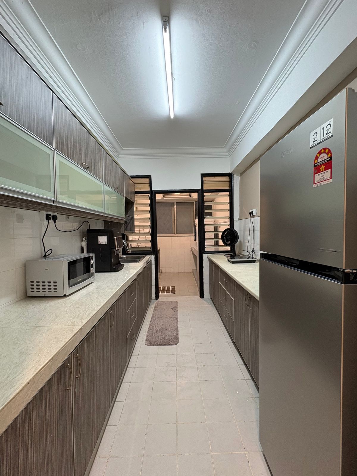 Shared galley kitchen with fridge, microwave, water dispenser, and cabinets