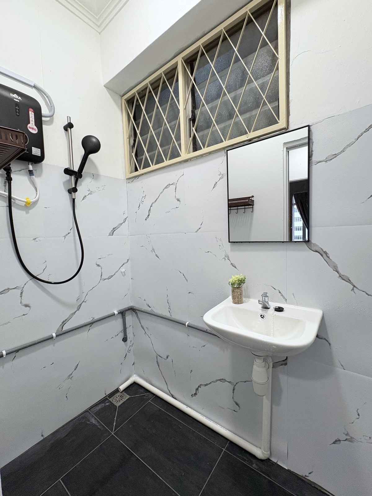 Shared bathroom with marble-style walls, shower, basin, and mirror